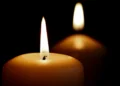 Primo piano di una candela accesa con una seconda candela sfocata sullo sfondo, immagine simbolica utilizzata per rappresentare lutto, ricordo e cordoglio.
