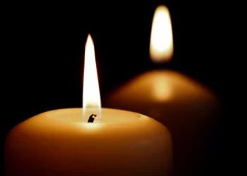 Primo piano di una candela accesa con una seconda candela sfocata sullo sfondo, immagine simbolica utilizzata per rappresentare lutto, ricordo e cordoglio.