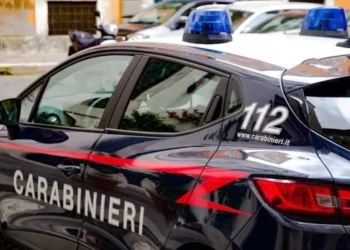 Auto di servizio dei Carabinieri parcheggiata in strada con lampeggianti blu, durante un intervento delle forze dell'ordine.