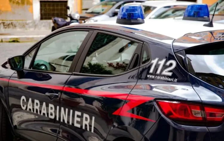 Auto di servizio dei Carabinieri parcheggiata in strada con lampeggianti blu, durante un intervento delle forze dell'ordine.