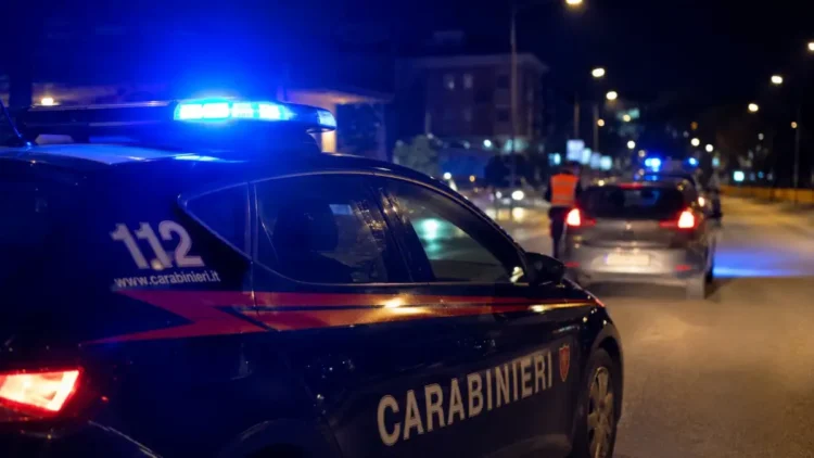 Auto dei Carabinieri con lampeggianti accesi durante un controllo stradale notturno in una strada urbana