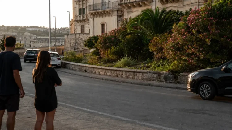 La circonvallazione di Ragusa Ibla con il muretto in pietra, oleandri in fiore e il palazzo barocco sullo sfondo