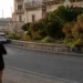 La circonvallazione di Ragusa Ibla con il muretto in pietra, oleandri in fiore e il palazzo barocco sullo sfondo