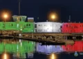 La sede della Capitaneria di Porto di Pozzallo illuminata con i colori del tricolore italiano riflessi sul mare di notte.