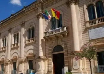 Facciata del Palazzo Comunale di Scicli con le bandiere italiana, europea e siciliana esposte sul balcone principale