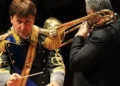 Maestro direttore della Banda musicale della Guardia di Finanza durante un'esibizione con un musicista al trombone.