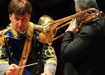 Maestro direttore della Banda musicale della Guardia di Finanza durante un'esibizione con un musicista al trombone.