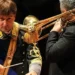 Maestro direttore della Banda musicale della Guardia di Finanza durante un'esibizione con un musicista al trombone.