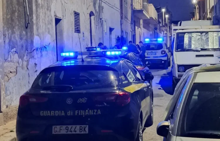Auto della Guardia di Finanza con lampeggianti blu accesi in un vicolo notturno durante un servizio di controllo del territorio