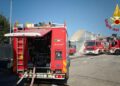 Tre autopompe dei Vigili del fuoco schierate in un piazzale davanti a un edificio parzialmente crollato