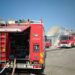 Tre autopompe dei Vigili del fuoco schierate in un piazzale davanti a un edificio parzialmente crollato