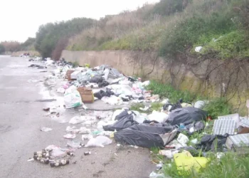 Cumuli di rifiuti abbandonati lungo una strada di campagna nel territorio di Vittoria, con sacchi di spazzatura e materiali di vario genere accumulati ai margini della carreggiata
