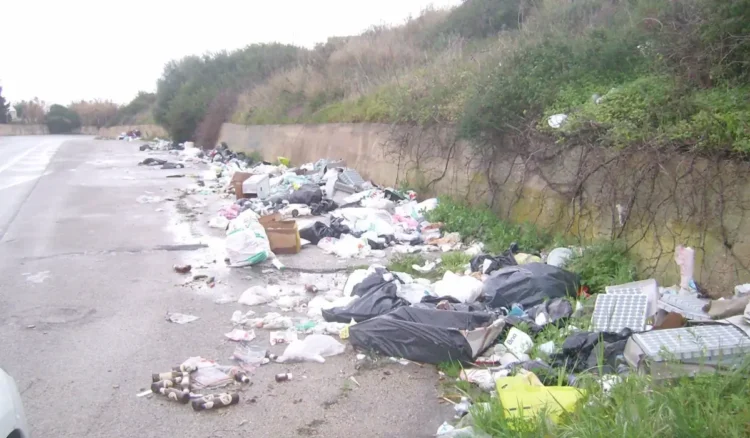 Cumuli di rifiuti abbandonati lungo una strada di campagna nel territorio di Vittoria, con sacchi di spazzatura e materiali di vario genere accumulati ai margini della carreggiata