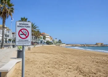 Cartello di divieto di fumo sulla spiaggia di Marina di Ragusa con il litorale, il lungomare e il mare sullo sfondo