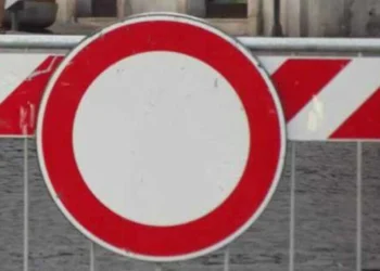 Segnale di divieto di transito posizionato davanti a una barriera stradale bianca e rossa che indica la chiusura temporanea della strada per lavori.