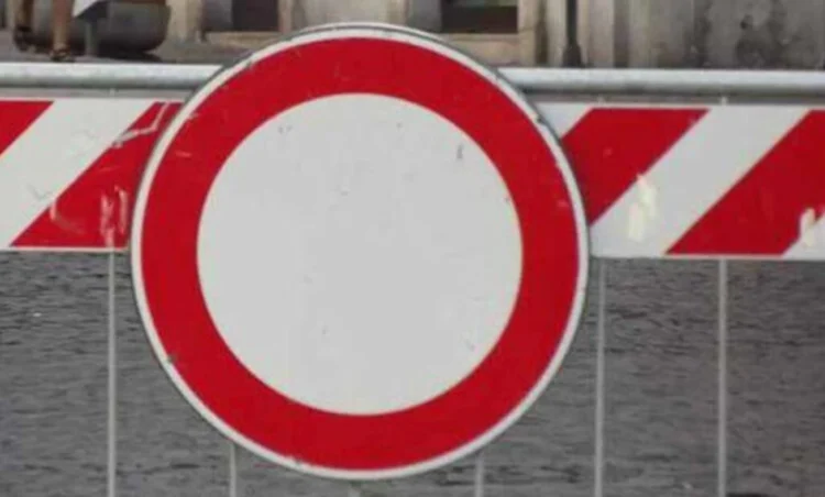 Segnale di divieto di transito posizionato davanti a una barriera stradale bianca e rossa che indica la chiusura temporanea della strada per lavori.