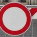 Segnale di divieto di transito posizionato davanti a una barriera stradale bianca e rossa che indica la chiusura temporanea della strada per lavori.