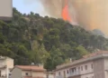 Vasto incendio sulla collina di Monserrato a Modica, con alte fiamme e una densa colonna di fumo sopra la pineta, osservata dalle abitazioni sottostanti