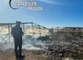 Un Carabiniere osserva un piccolo rogo di rifiuti plastici e vegetali in un'area agricola ad Acate durante un'operazione di contrasto alla combustione illecita dei rifiuti