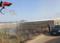 Un carabiniere documenta un'area con rifiuti agricoli bruciati accanto a serre nella contrada Dirillo, a Vittoria, durante un controllo contro il fenomeno delle fumarole