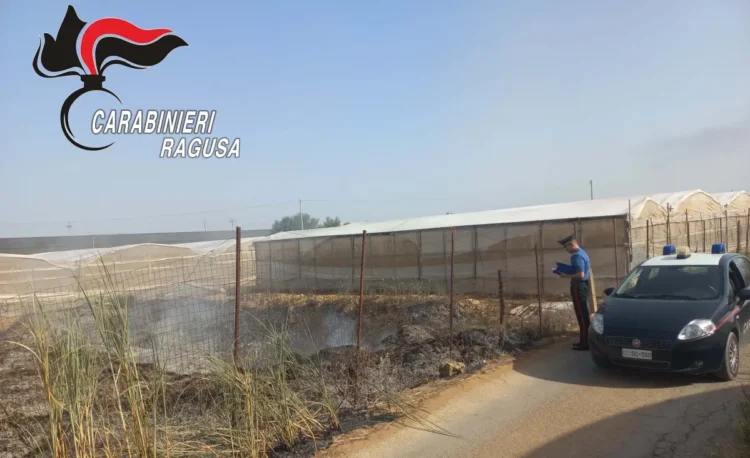 Un carabiniere documenta un'area con rifiuti agricoli bruciati accanto a serre nella contrada Dirillo, a Vittoria, durante un controllo contro il fenomeno delle fumarole