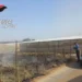 Un carabiniere documenta un'area con rifiuti agricoli bruciati accanto a serre nella contrada Dirillo, a Vittoria, durante un controllo contro il fenomeno delle fumarole