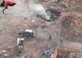 Veduta aerea dell'intervento dei Carabinieri in un'area di Scoglitti interessata da un rogo di rifiuti speciali, con fumo visibile e mezzi dell'Arma sul posto.