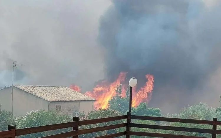 Incendio a Monserrato, a Modica, con alte fiamme e una densa nube di fumo nero a pochi metri dalle abitazioni della zona.