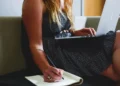 Giovane lavoratrice utilizza un computer portatile mentre prende appunti, immagine di repertorio sul bonus giovani 2026 per la stabilizzazione dei contratti di lavoro