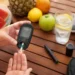 Persona che misura la glicemia con un glucometro accanto a frutta fresca, un bicchiere d'acqua con limone e scarpe da ginnastica, simboli di idratazione, alimentazione sana e attività fisica durante l'estate.