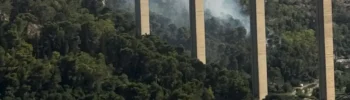 Incendio boschivo sotto il ponte Guerrieri, in via Fiumara tra Modica e Scicli, con colonne di fumo che si alzano dalla vegetazione mentre sono in corso le operazioni di spegnimento