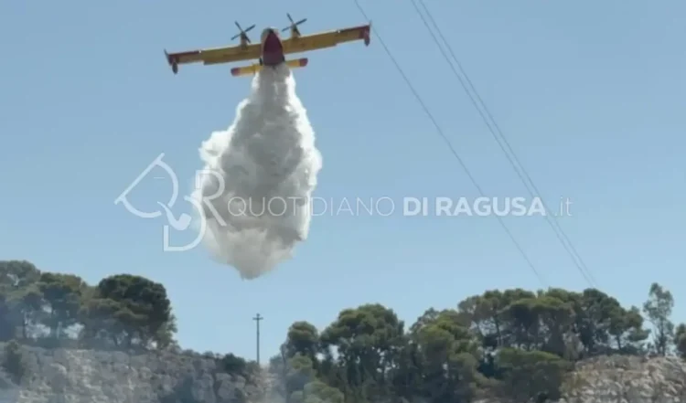 Un canadair effettua un lancio d'acqua sull'incendio che interessa la collina di Monserrato, a Modica, durante le operazioni di spegnimento