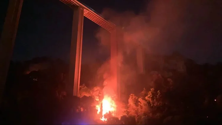 Incendio sul costone di Monserrato a Modica durante la notte con fiamme visibili sotto il viadotto
