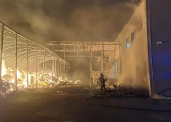 Un vigile del fuoco contrasta le fiamme nel deposito della Repack srl sulla SP 85, con la struttura metallica visibilmente danneggiata