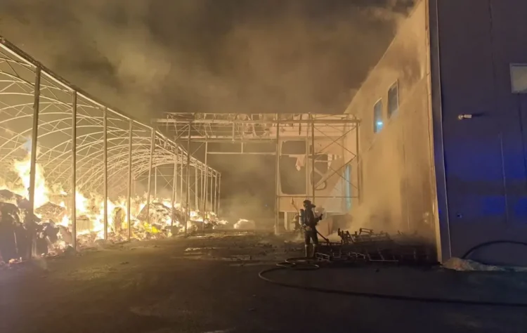 Un vigile del fuoco contrasta le fiamme nel deposito della Repack srl sulla SP 85, con la struttura metallica visibilmente danneggiata