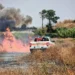 Vigili del fuoco e Protezione Civile impegnati nello spegnimento di un vasto incendio di sterpaglie a Santa Croce Camerina, con alte fiamme e una densa colonna di fumo.
