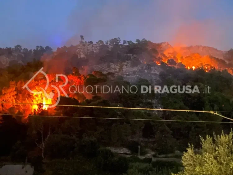 Vasto incendio sulla collina di Monserrato a Modica, con diversi focolai attivi tra la vegetazione e una densa colonna di fumo al tramonto