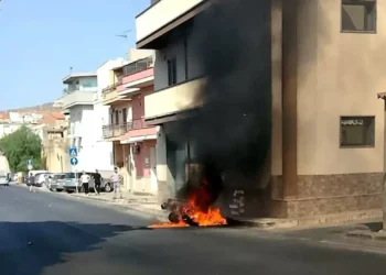 Veicolo in fiamme contro un edificio in una via residenziale di Comiso, con densa colonna di fumo nero che sale verso il cielo