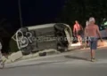 Auto ribaltata su un fianco dopo un incidente stradale a Sampieri, con alcuni residenti presenti sul luogo dell'impatto