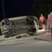 Auto ribaltata su un fianco dopo un incidente stradale a Sampieri, con alcuni residenti presenti sul luogo dell'impatto