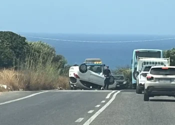 Auto bianca ribaltata a ruote all'aria sulla SP 25 vicino al mare, con agenti sul posto e traffico fermo in coda