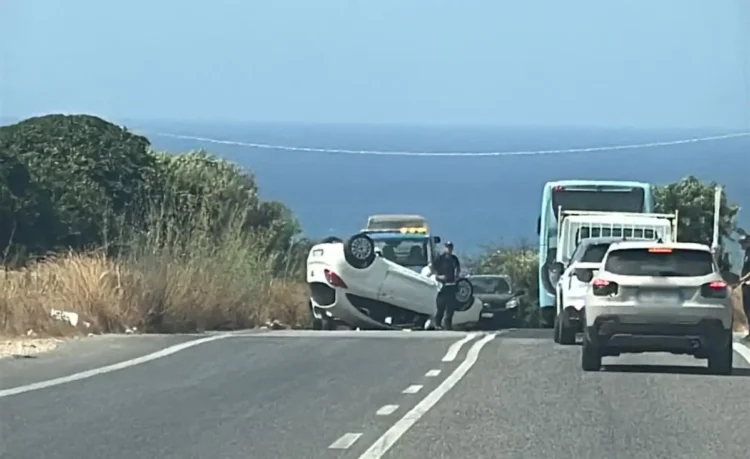 Auto bianca ribaltata a ruote all'aria sulla SP 25 vicino al mare, con agenti sul posto e traffico fermo in coda