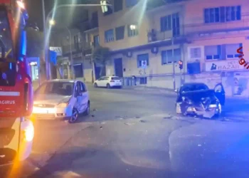 Due auto con i frontali distrutti sull'asfalto di un incrocio notturno a Ragusa, con un mezzo dei Vigili del Fuoco sul lato sinistro.