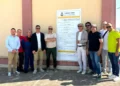 Gruppo di persone in posa davanti al pannello di cantiere del PIP di Comiso, con il logo del Comune di Comiso.