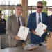 Il Questore di Ragusa e il presidente del Consorzio Siciliano di Riabilitazione mostrano la convenzione firmata al Lido della Polizia di Stato di Caucana, affiancati da due agenti della Polizia di Stato