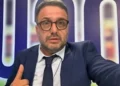 Primo piano del giornalista sportivo Luigi (Luca) Esposito mentre scatta un selfie puntando il pollice verso l'alto davanti a uno sfondo televisivo.