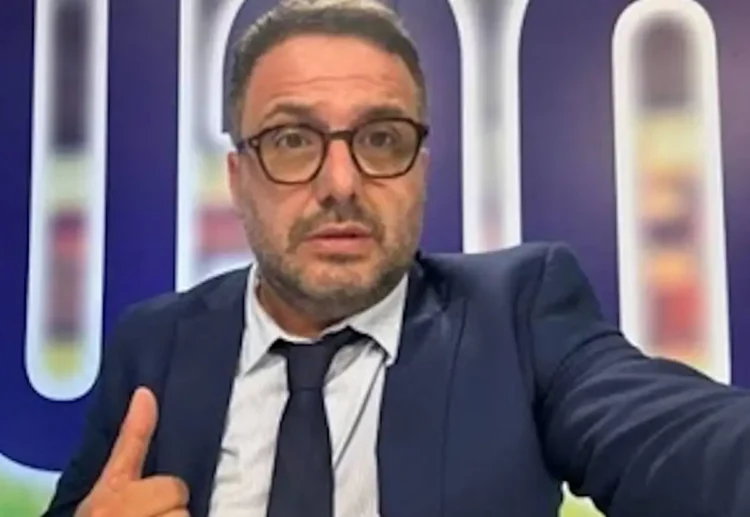 Primo piano del giornalista sportivo Luigi (Luca) Esposito mentre scatta un selfie puntando il pollice verso l'alto davanti a uno sfondo televisivo.