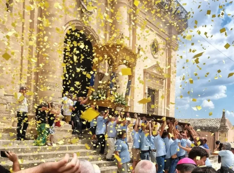 Portatori in azzurro reggono il fercolo della Madonna della Neve sotto una pioggia di coriandoli gialli a Giarratana
