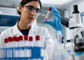 Scienziata in un laboratorio di genetica osserva una provetta con un campione biologico durante un'attività di ricerca sulle malattie genetiche rare.