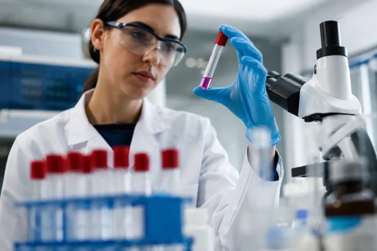 Scienziata in un laboratorio di genetica osserva una provetta con un campione biologico durante un'attività di ricerca sulle malattie genetiche rare.
